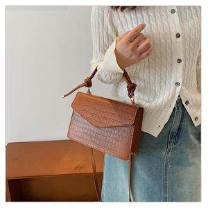 Detail of brown stone pattern crossbody bag showing the knotted cylindrical handle and texture