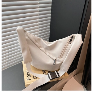 Detail of minimalist cream crossbody bag with adjustable strap and buckle on books