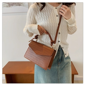 Brown crocodile embossed leather handbag with twisted handle shown on model's shoulder