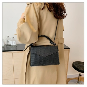 Detail shot of a black stone-pattern crossbody bag worn by a model in a minimal setting