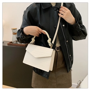 Detail of white crocodile embossed mini crossbody bag with unique knot handle design