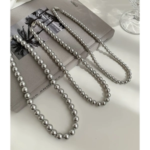 Lustrous grey pearl necklaces in various sizes with silver metal clasps on a minimal desk