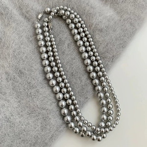 Detailed view of a triple-layered silver-grey pearl necklace on soft mohair fabric