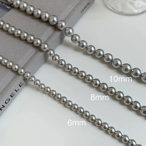 Macro detail of 6mm, 8mm, and 10mm grey pearls with high metallic luster and smooth texture