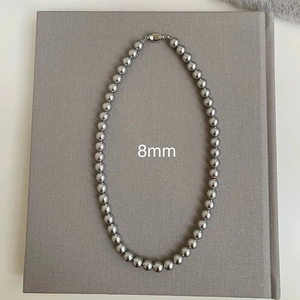 Close-up of 8mm grey pearl necklace featuring a silver metallic clasp on grey fabric