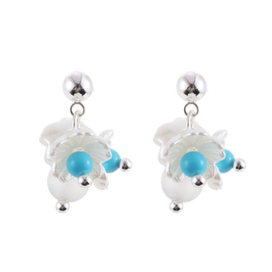 Close-up of silver flower earrings with white resin petals and turquoise beads