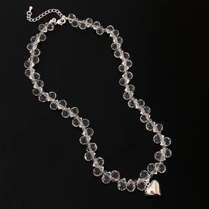Elegant clear crystal beaded necklace with a silver heart pendant on black background