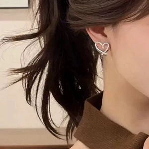 Elegant silver open heart stud earrings with cubic zirconia stones worn by a model