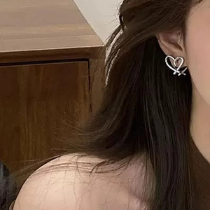 Elegant hollow heart earrings with zircon inlay worn by a model in a warm setting