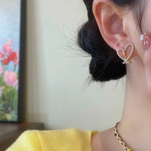 Close-up of elegant gold heart earrings with micro-set zircons on a model's ear
