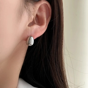 Close-up of polished silver teardrop earrings on model for a minimalist style