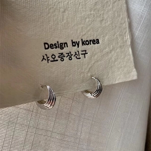 Macro shot of silver textured hoop earrings with relief stripes on display card