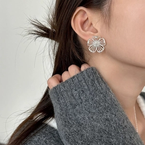 Silver hollow flower earrings with shimmering petals worn on a model in a minimal style