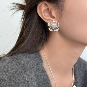 Elegant hollow flower stud earrings in silver finish worn by a model in a close-up shot
