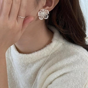 Close-up of elegant hollow flower earrings with delicate silver texture on model