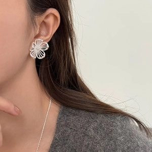 Close-up of a silver hollow flower earring worn by a model with a knit sweater