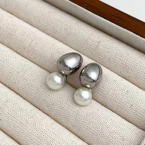 Detail of silver organic pebble stud earrings with white lustrous pearls on velvet