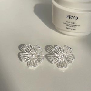 Silver hollow flower stud earrings with central sparkling crystals on a clean surface