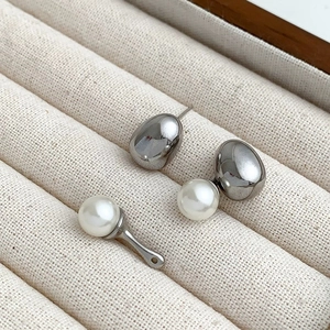 Macro detail of silver metal irregular stud earrings with glossy pearls in a jewelry box