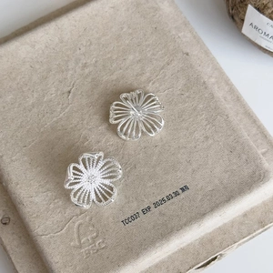 Macro shot of silver hollow flower earrings showing textured petals and craft details