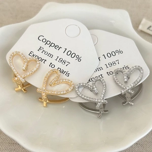 Boucles d'oreilles cœurs en or et argent avec zircons incrustés dans une coupelle en céramique