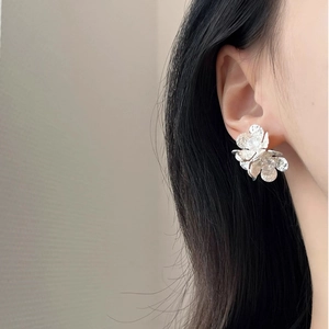 Elegant zircon flower stud earrings in silver finish worn by a model on a plain background