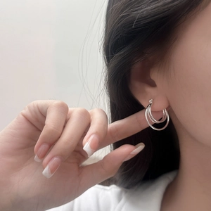 Three-layer nested silver hoop earrings for women with polished finish on model