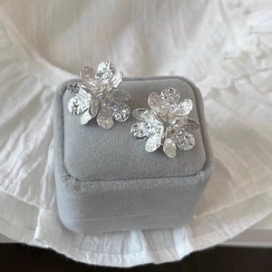 Macro shot of silver flower stud earrings with hammered texture and zircon centers