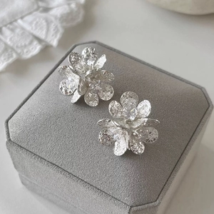 Detail view of silver floral earrings with zircons and hammered texture on velvet