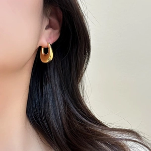 Polished gold U-shaped metal chunky hoop earrings shown on a model for minimalist style