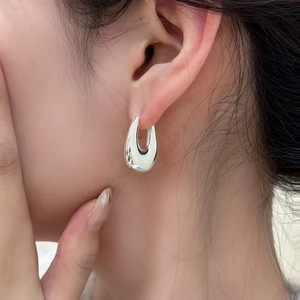 Close-up of a high-polished silver U-shaped drop earring on a model's ear
