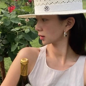 Polished silver chunky hoop earrings worn by a woman with a chic straw hat