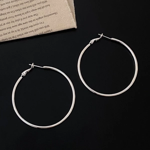 Minimalist large silver circle hoop earrings displayed on a dark textured background