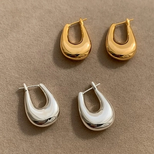 Close-up of polished gold and silver U-shaped chunky hoop earrings on velvet