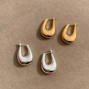 Close-up of minimalist U-shaped hoop earrings in polished gold and silver finishes