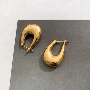 Close-up of chunky gold-tone U-shaped earrings with high-polish metallic finish