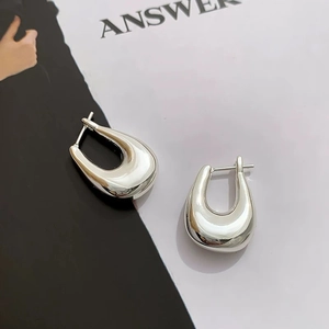 Detailed macro shot of silver U-shaped earrings with a polished mirror finish on a magazine