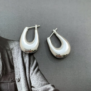 Close-up of polished silver U-shaped hoop earrings on minimalist grey background