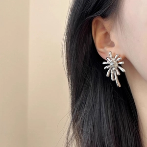 Close-up of polished silver firework stud earrings worn by a model for a chic look
