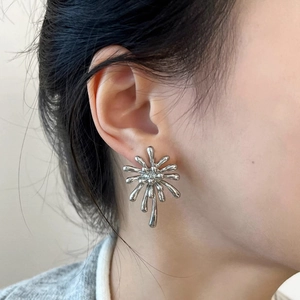Close-up of a silver fluid firework stud earring on ear with metallic luster finish