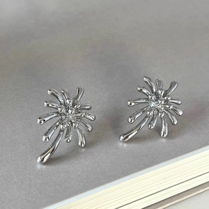 Detailed close-up of radiant silver firework earrings with a high-polished metallic finish