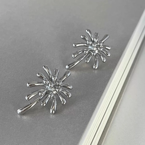 Macro shot of silver fireworks stud earrings with reflective liquid metal texture