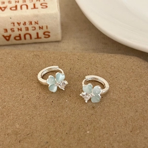 Macro detail of silver floral hoop earrings with mint blue stones and zircon heart