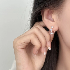 Elegant C-shaped hoop earrings with blue star zircons on model with soft lighting