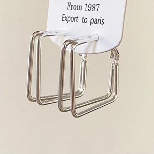 Detailed close-up of silver double-layered geometric square earrings on a white display card