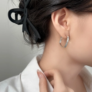 Minimalist silver square geometric earrings with textured finish on a female model