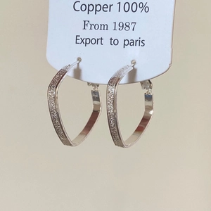 Macro detail of geometric silver plated copper earrings with frosted matte finish texture