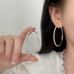 Grandes boucles d'oreilles créoles argentées serties de zircons sur mannequin