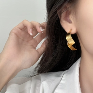 Minimalist twisted gold brushed metal drop earrings for women shown on model