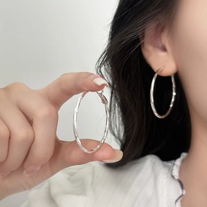Boucles d'oreilles créoles argentées texturées avec motif en spirale et design géométrique